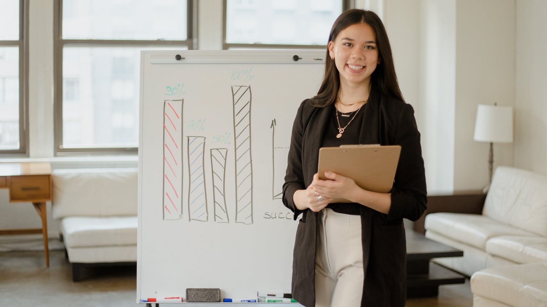 woman in black blazer standing beside a whiteboard with graphs